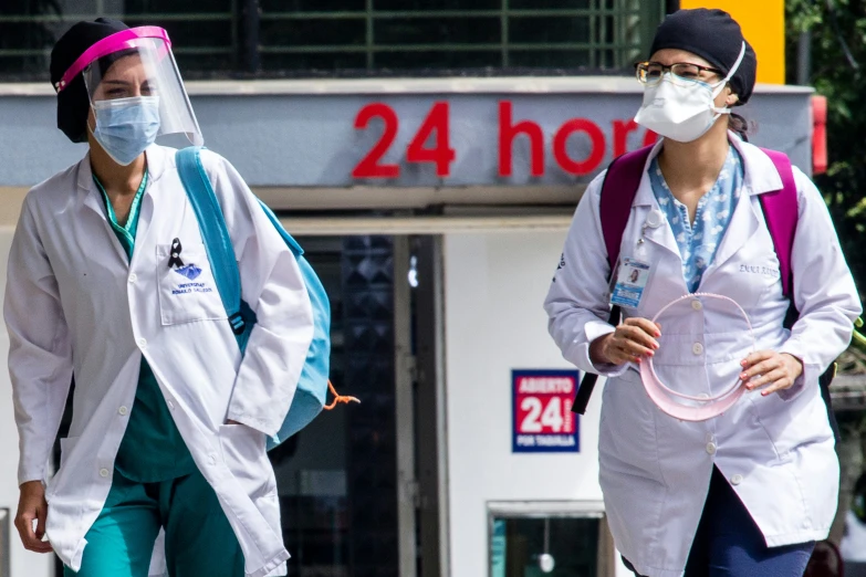 two people walking down a street with masks on