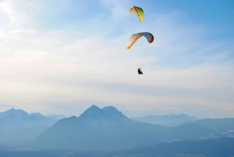 the parachutes are being flown in the sky by two people