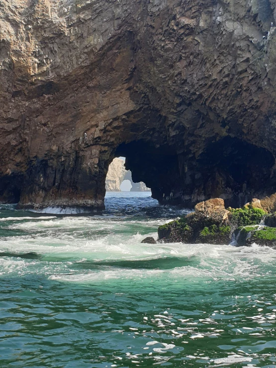 a person wading through the water from a rock cave