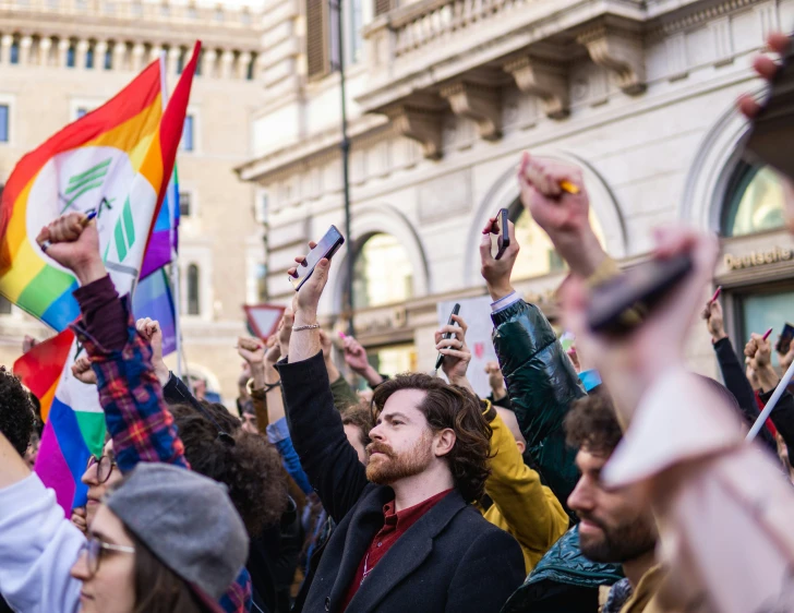 there are people holding rainbow flags at this public rally