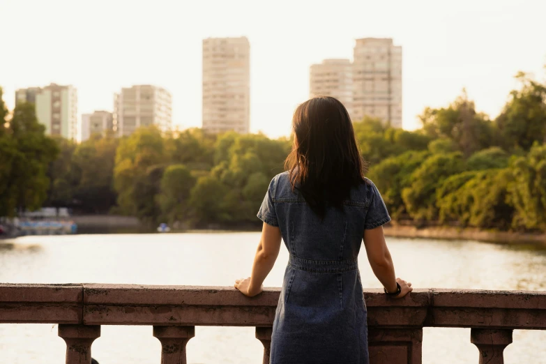 a woman standing at a railing looking over a river and a city skyline