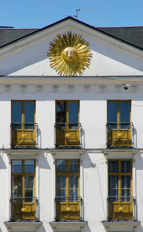 a very large white building with windows and a sun