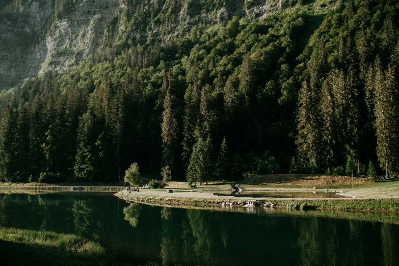 a group of men resting on the side of a lake surrounded by mountains