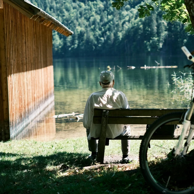 a woman sitting on a bench next to a lake