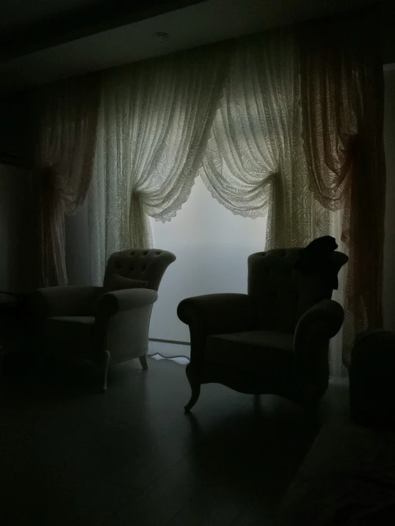 a dimly lit room with two chairs and one chair facing a window