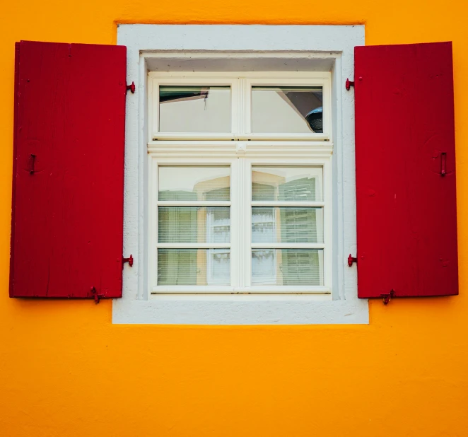 window and red shutters on yellow building