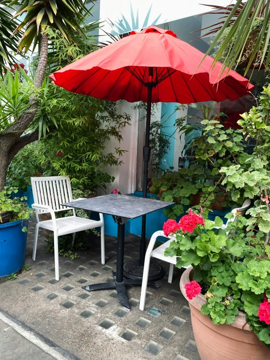 two white garden chairs sitting next to each other under an umbrella