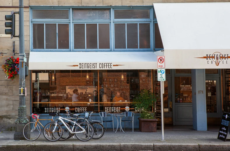 three bicycles are parked outside of a coffee shop