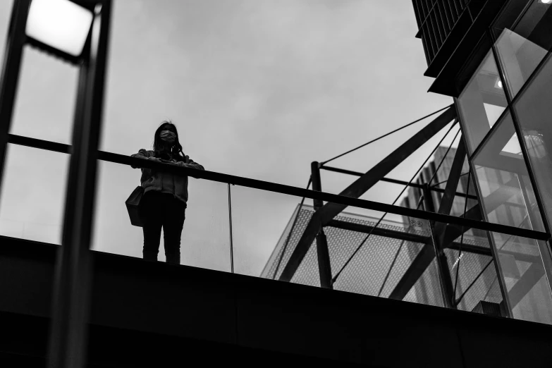 a woman stands on the edge of a bridge