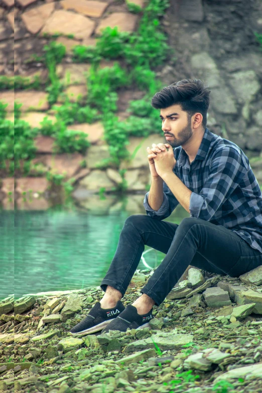 a man in jeans sitting on rocks and drinking