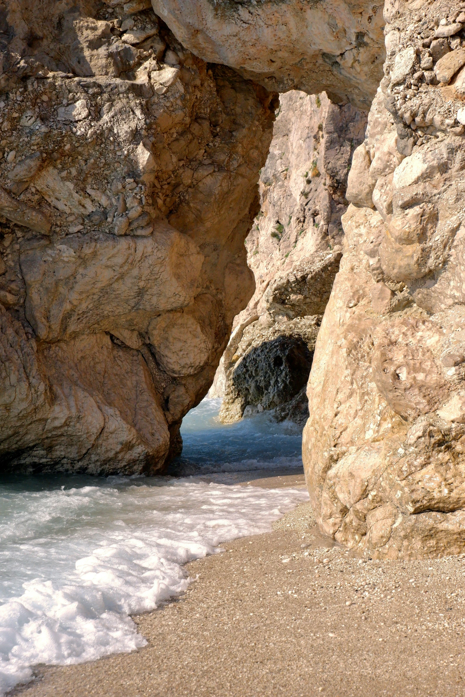 a large rock formation sitting in the ocean next to a beach