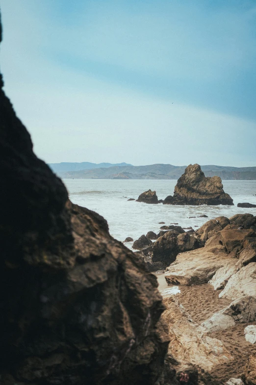 a view of the ocean, rocks and mountains