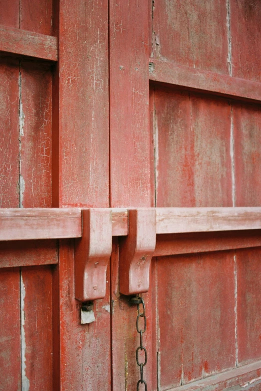 two open red doors with a metal chain hanging off them