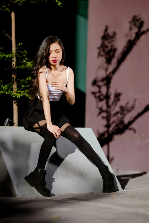 a woman sitting on the edge of a ramp in black tights and white tank top