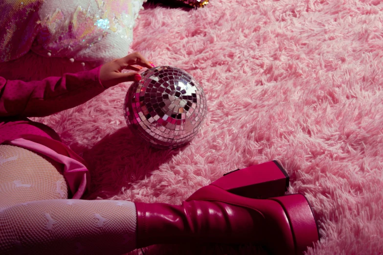 a close up of a person holding a ball on top of a furry surface