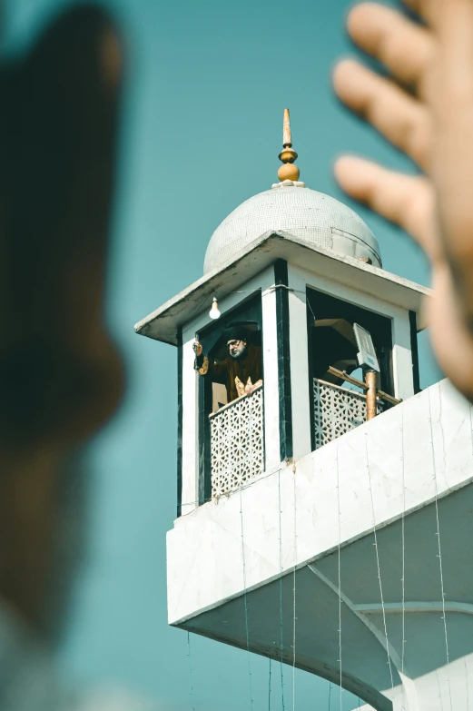 a person reaches up to take a picture of a building and the tower