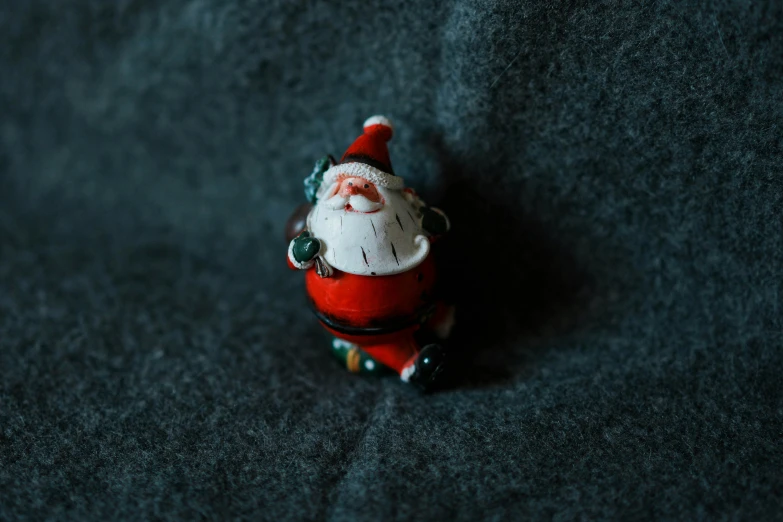 santa clause toy figurine posed on dark colored carpet