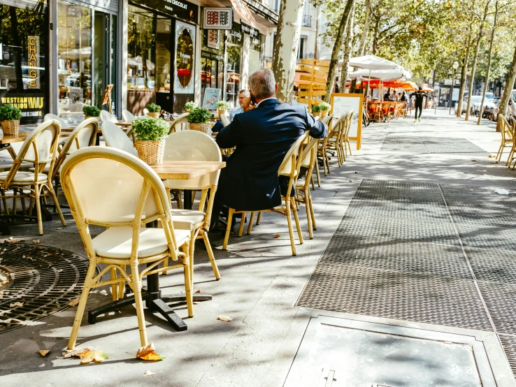 an elderly gentleman sitting at an outdoor table looking out on the sidewalk