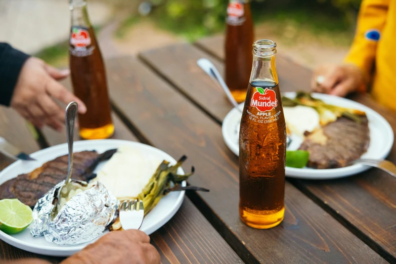 people eating steak and drinking beers at an outdoor table