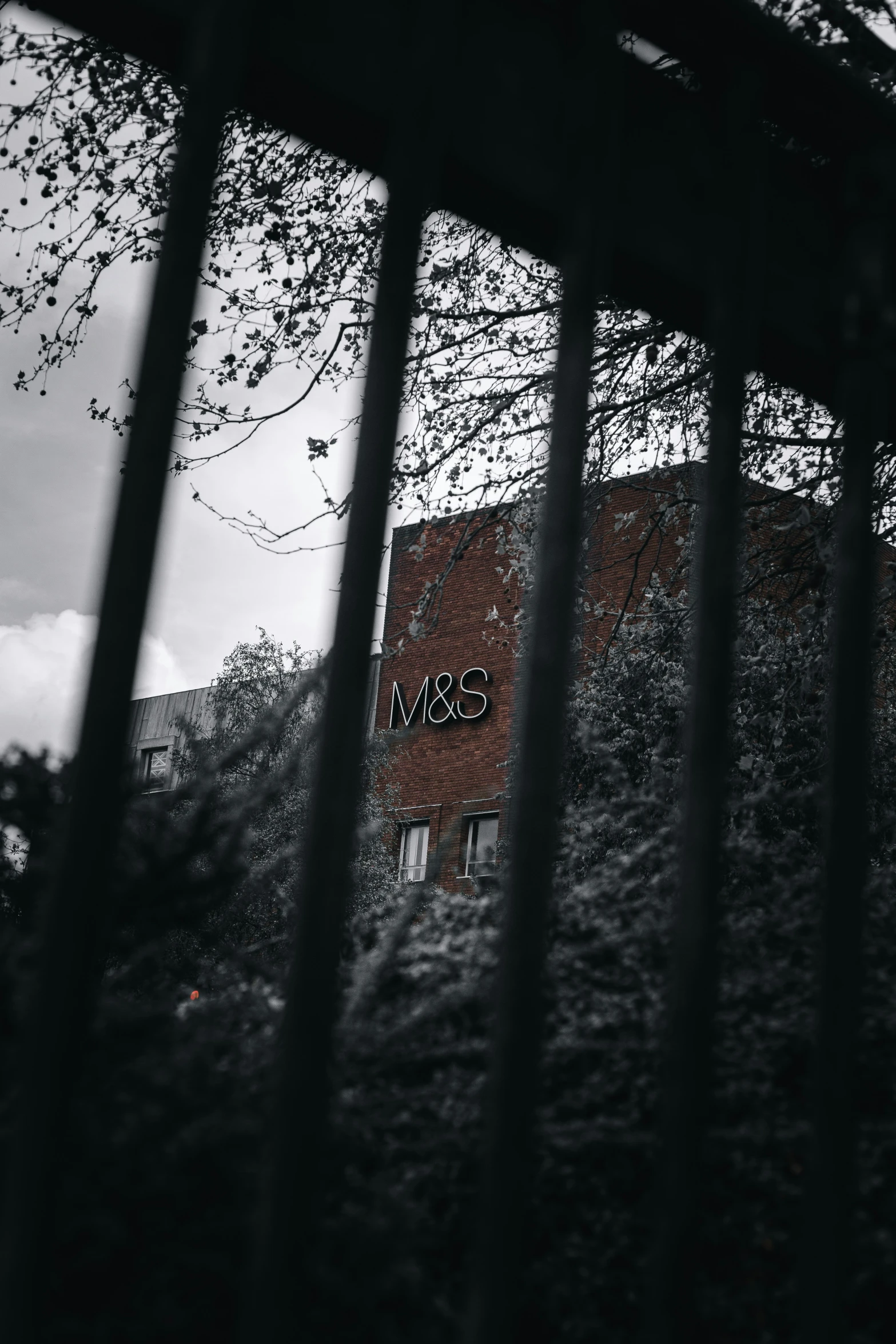 the brick wall is behind the bars of the fence