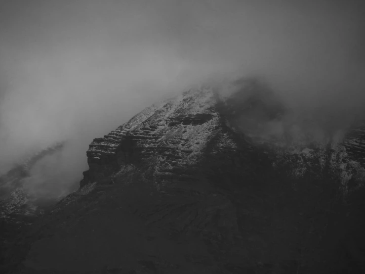 a mountain is shown covered with clouds and snow