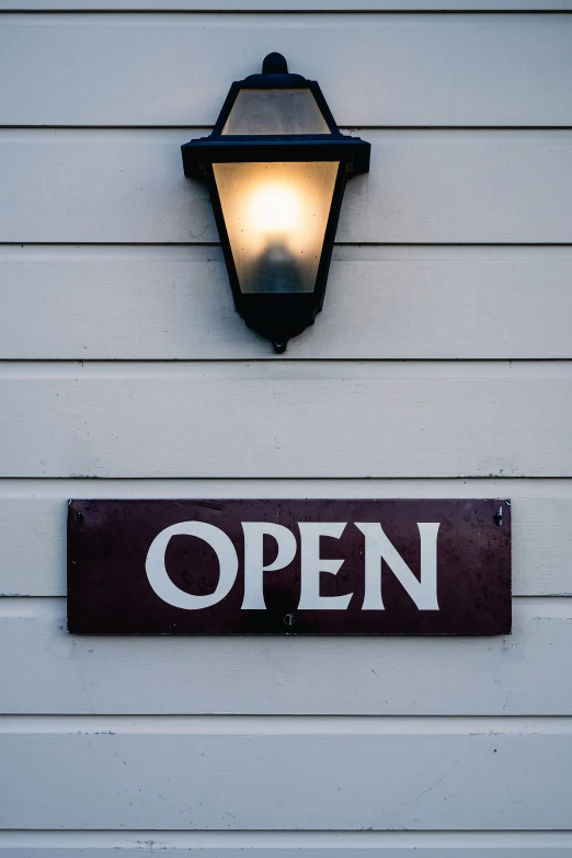 the lit light on the side of a building is next to a open sign