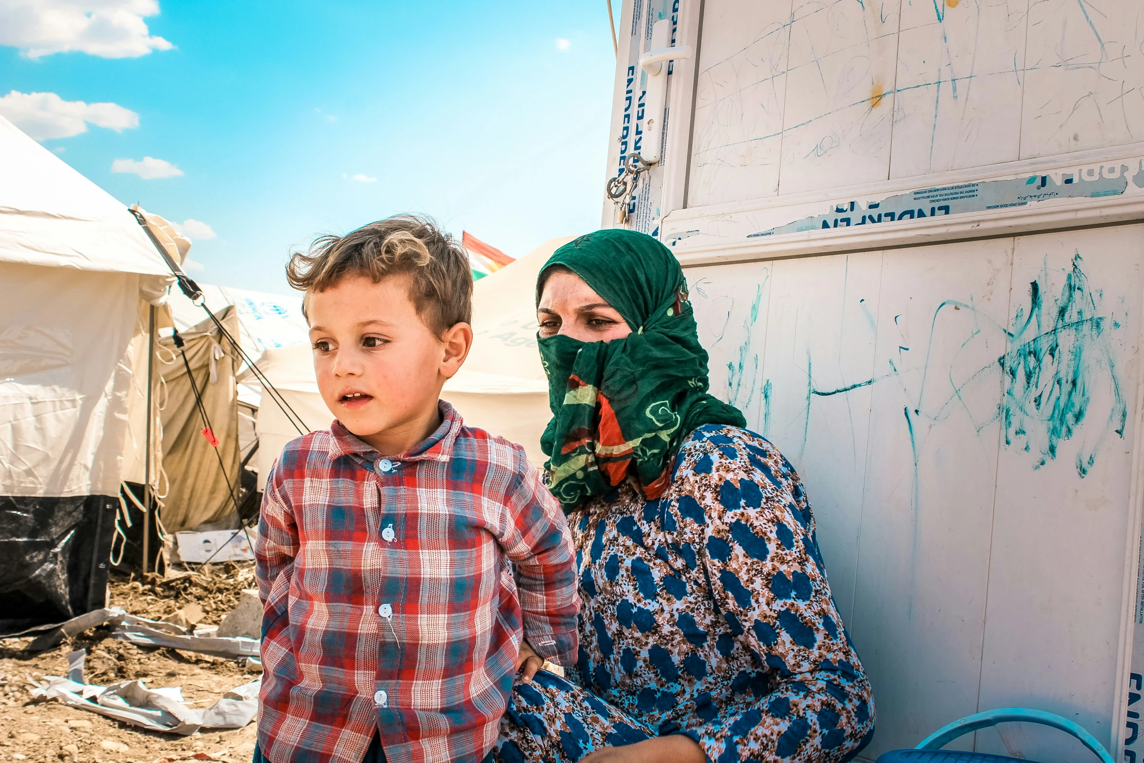 a boy and a woman wearing hijabs on a dirt lot