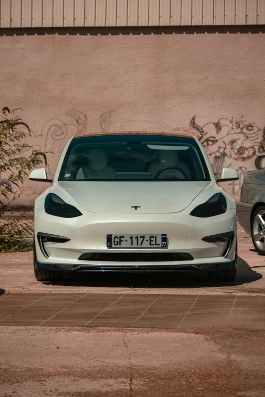 a white electric vehicle parked by a wall