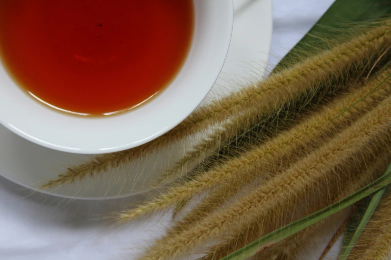 there is a bowl of tea with a stick of green