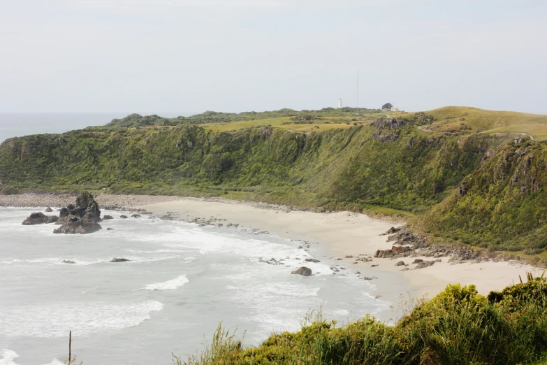 a rocky beach is next to some green mountains