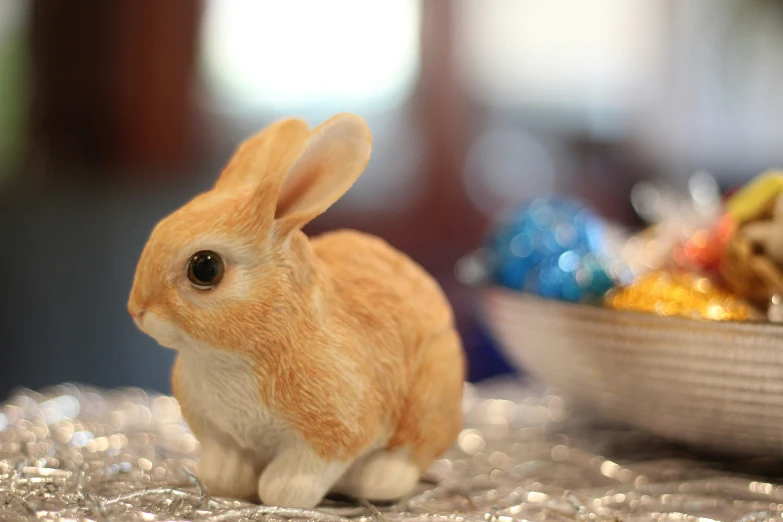 a little bunny doll next to a small bowl of eggs