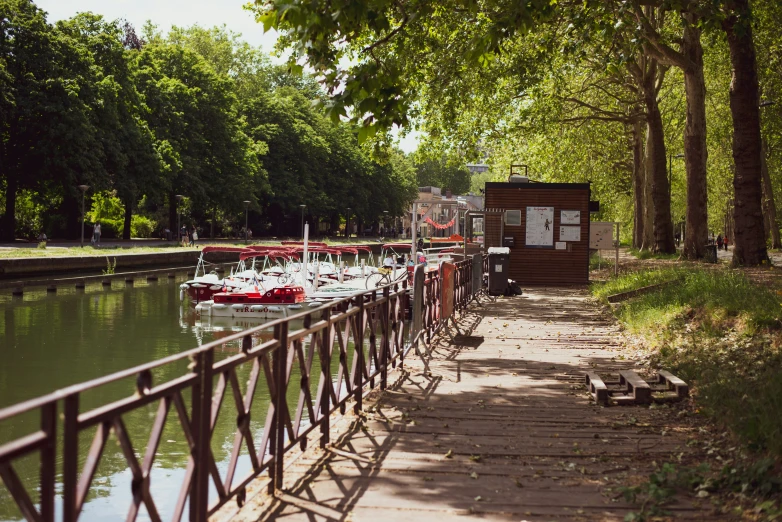 the view of several boats docked along the canal near many trees