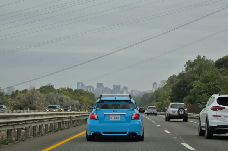 the rear view of a blue car driving down a street