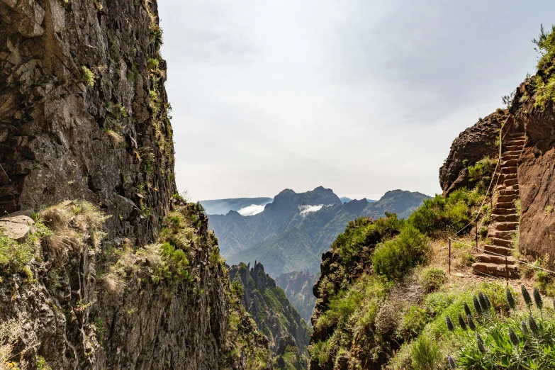 the view from a path along a canyon with steep mountain ranges