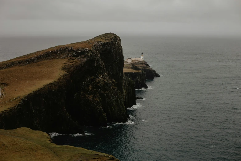 a lone lighthouse on the side of an ocean with dark water