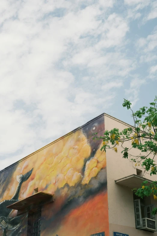 the building is painted yellow and orange with black birds flying in the air