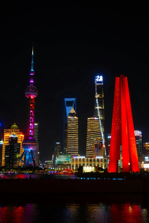 a colorful night scene with tall buildings on the other side