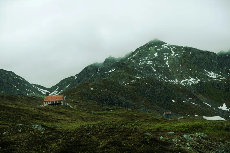 a cabin on a hill with snow on the mountain tops