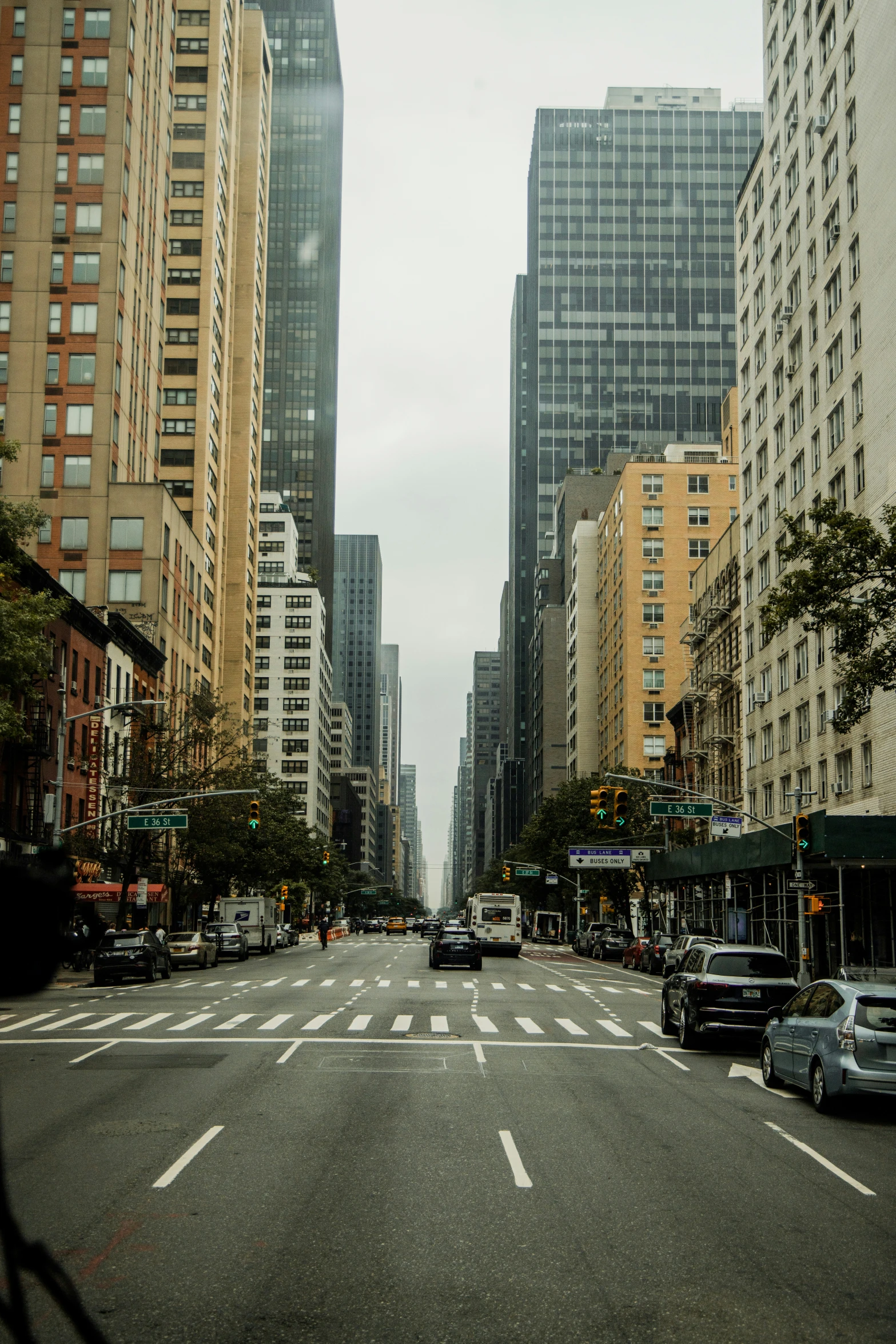 cars drive down a city street with tall buildings