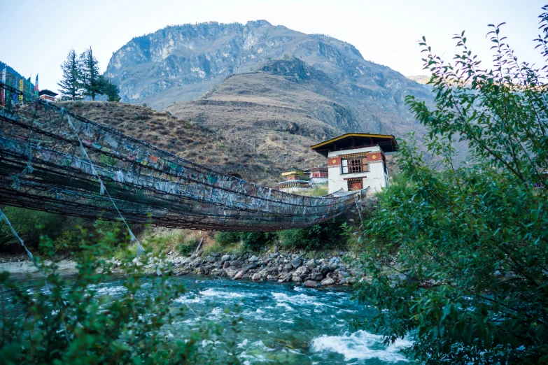 a very pretty house next to a stream in the mountains