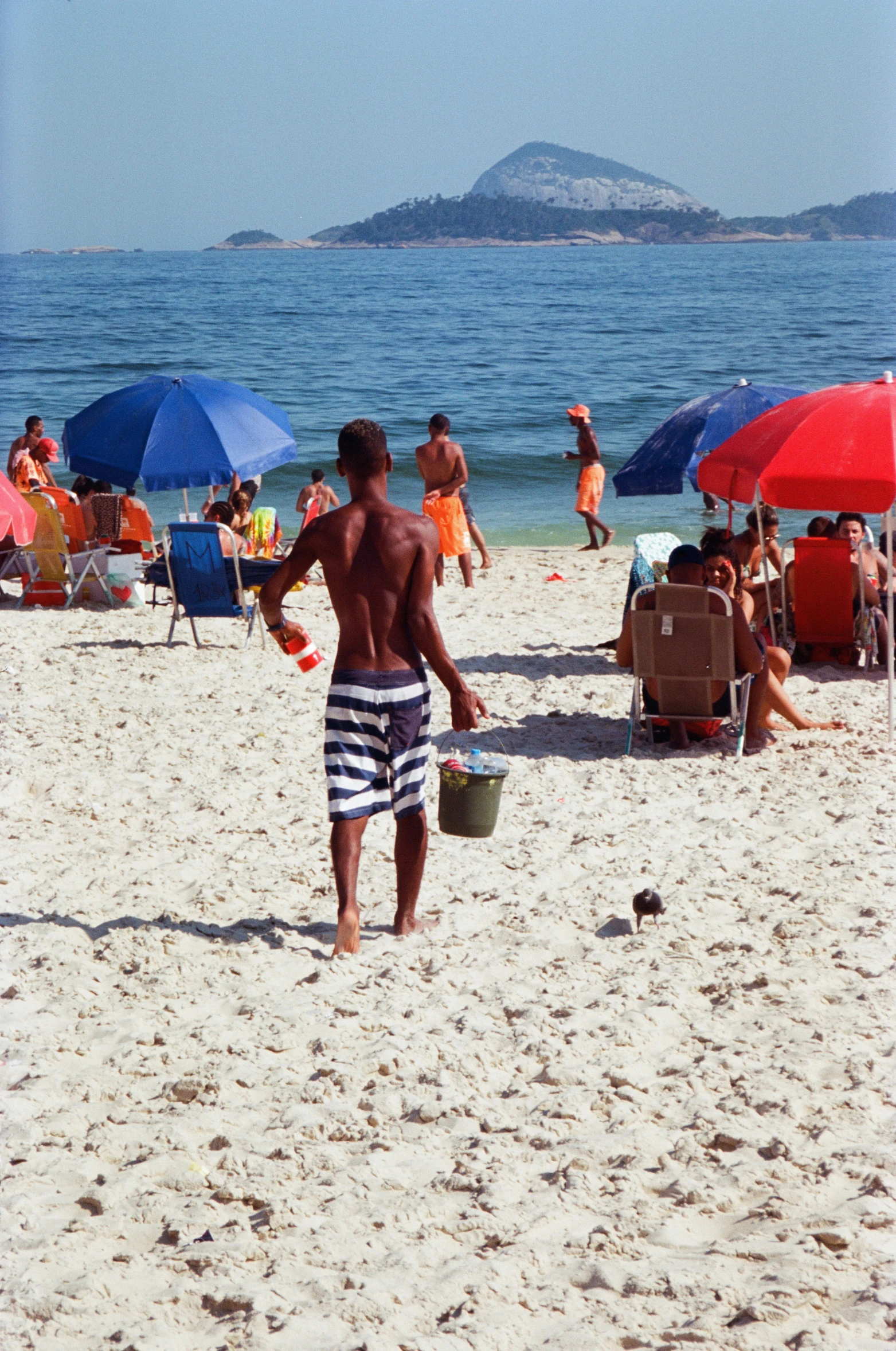 a man walking across a beach next to umbrellas