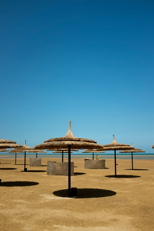 a bunch of straw umbrellas that are on a beach