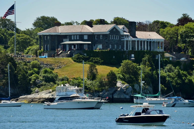 two boats are parked in the water near a large house