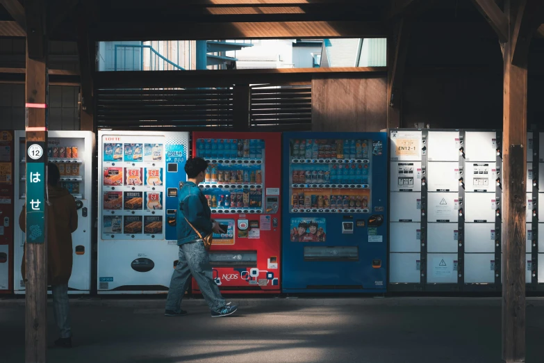 a man walking down a street past vending machines