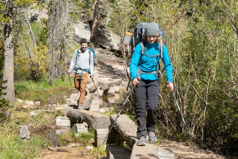 two people cross a small trail on a hike