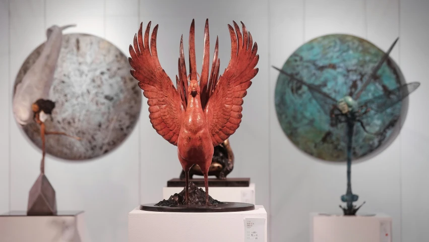 a group of sculptures with wings and a ball on display