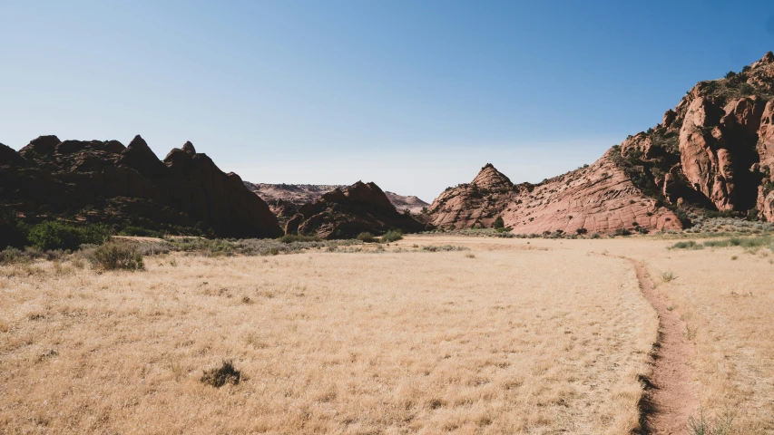 an open field with sand and rocks in the distance