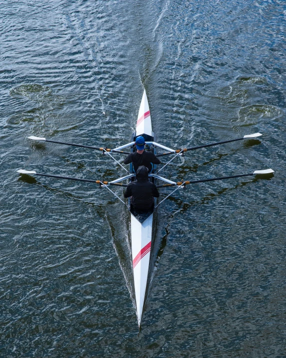 two people rowing down a body of water on long legs
