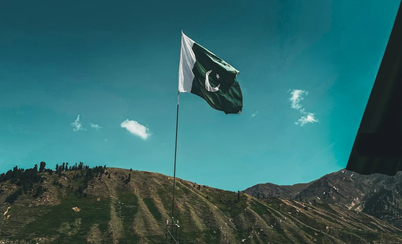 a flag flying high in the sky near a mountain