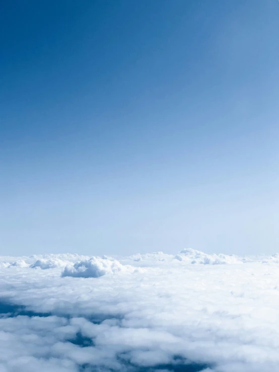 a plane flying above some white clouds on a clear day